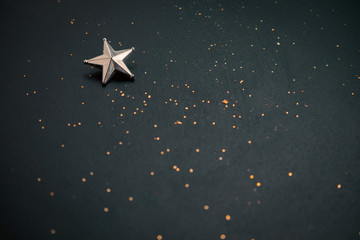 blurred dark festive background with golden glitters and metallic star