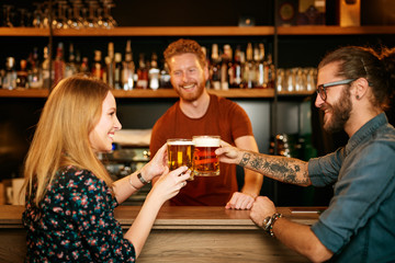 Friends standing in bar and toasting with beer.