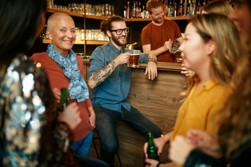 Naklejka premium Group of friends drinking beer, chatting and having good time at pub. Night out.