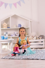 pretty little girl hugs a doll in white room