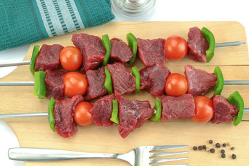 skewers of beef, pepper and raw tomato on a white background