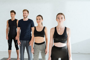 smiling young people in sportswear standing in mountain pose