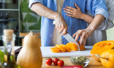 Unrecognizable couple cutting fresh pumpkin for cooking