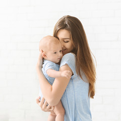 Portrait of cute infant child in arms of young mother