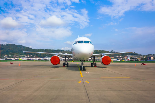 Passenger Aircraft Parked At The Airport With Covered Red Covers Engines.