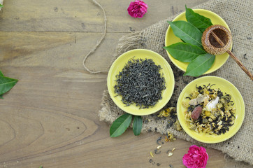 Assortment of dry tea and fresh tea leaves on wooden background