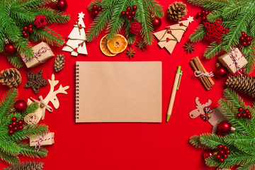 Fototapeta na wymiar Top view of notebook on red background made of Christmas decorations. New Year time concept