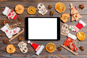 Top view of tablet on holiday wooden background. New Year decorations and toys. Christmas concept