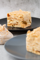Piece of cake Napoleon on blue plate on marble background, close up view. Traditional millefeuille dessert with puff pastry and custard, copy space. Vertical photo. Photo for bakery menu.