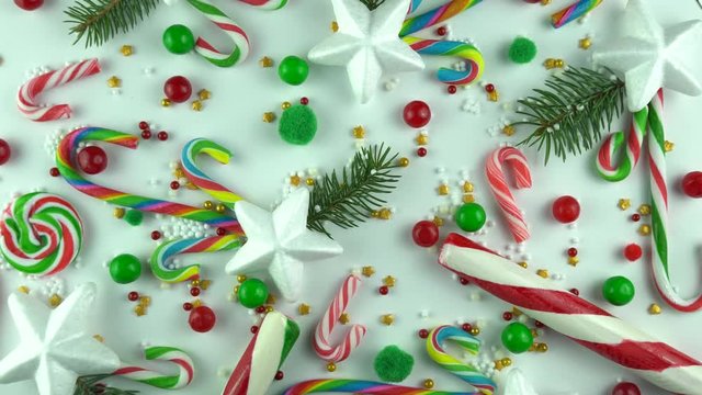 Christmas Eve holiday mood close up background. Winter Merry days  traditional ornament of candy canes and various gold sprinkles, peppermint and cinnamon lollipops rotation in slow motion. Top view.