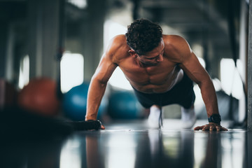 Portrait of a handsome man doing push ups exercise with hand in fitness gym