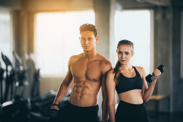 Plakat Sporty young couple with dumbbells in functional training fitness gym