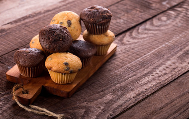 Assorted fresh delicious muffins on wooden background