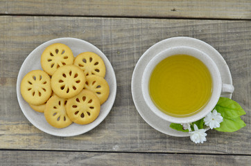 Fresh jasmine tea in cup with cookies on wooden table