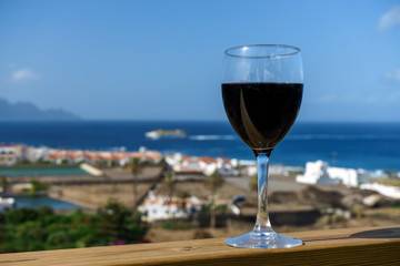 Beautiful wineglass with red wine, standing on the open deck against the backdrop of sea waves. Side view, close-up. Concept of leisure and travel