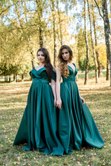 Obraz na płótnie Canvas Ladies in elegant green dresses walking in autumn park. Brunette girl Dreamy young girls laughing on the outdoors
