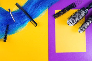 Piece of blue hair. Professional hairdresser tools, set with various accessories on bright purple and yellow background. Hair and beauty salon. Beauty concept with copy space
