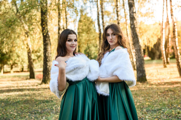 Fototapeta premium Ladies in elegant green dresses walking in autumn park. Brunette girl Dreamy young girls laughing on the outdoors