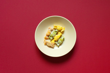 Stuffed Pasta with caramelle shape served in a cream bowl over a red background