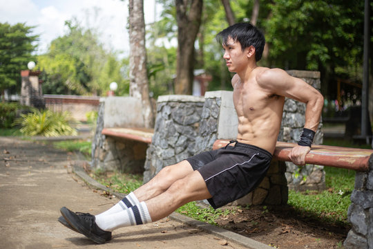 Asian man is doing bench triceps dips at park,street work out concept