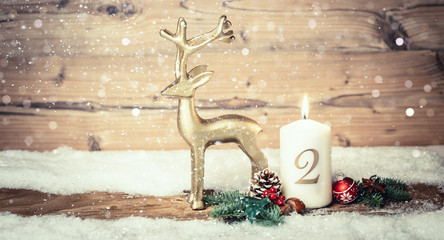 white, burning candle in winter landscape with fir and christmas decoration