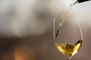 White wine being poured in wineglass, closeup