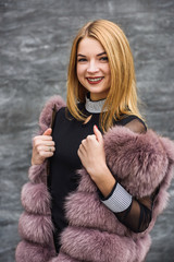 Stylish woman in fur coat posing outdoors on city street. Fashion concept