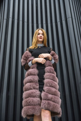 Urban fashion. Portrait of fashion woman in fur coat posing on city street