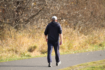 Elderly man taking a walk in a park on a sunny day.