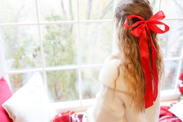 Young beautiful woman sitting home by the window wearing warm sweater with long hair