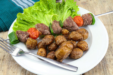 grilled potatoes and beef skewer on a plate
