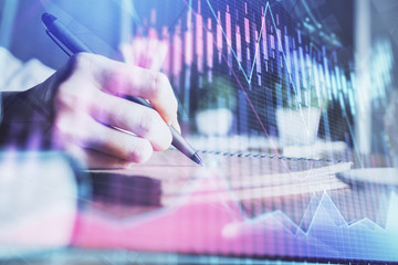 Financial forex charts displayed on woman's hand taking notes background. Concept of research. Double exposure