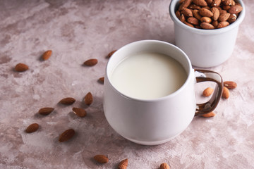 Alternative food and drink. Homemade almond milk in a cup, almond kernels on rustic background. Copy space