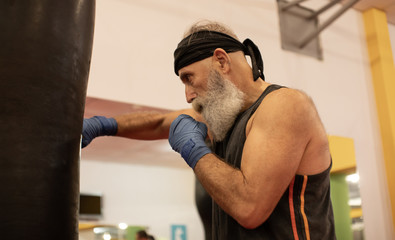 Fototapeta premium Senior male boxer ready to fight. Senior boxer in gloves boxing in gym