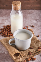 Homemade almond milk in bottle and Almond kernels on rustic background. Alternative food and drink