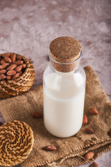 Homemade almond milk in bottle and Almond kernels on rustic background. Alternative food and drink