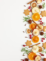  Christmas composition with cookies, dried oranges, cinnamon sticks and herbs on white background. Natural food ingredient for cooking or Christmas decor for home. Flat lay.