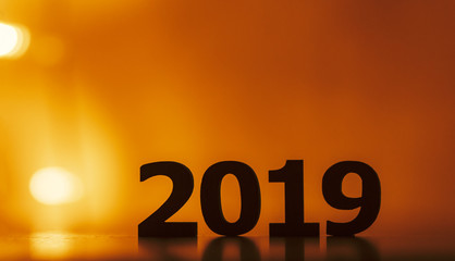 silhouette of wooden figures of date 2019 on a glowing bright background, concept new 2020 year replaces the old