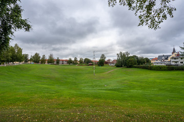 Autumn town landscape view of the large grassy pit Gropen on a green field in Leksand Sweden.