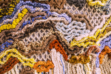 Fragment of a panel, connected from heterogeneous and multi-colored woolen threads, non-repeatable pattern, close-up, toned.