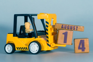 august 14th. Day 14 of month, Construction or warehouse calendar. Yellow toy forklift load wood cubes with date. Work planning and time management. summer month, day of the year concept
