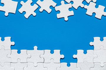 White jigsaw puzzle. White puzzle pieces on color background. Unfinished white jigsaw puzzle pieces on color background.