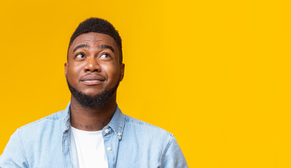 Cynical guy looking upwards at copy space on yellow background - obrazy, fototapety, plakaty