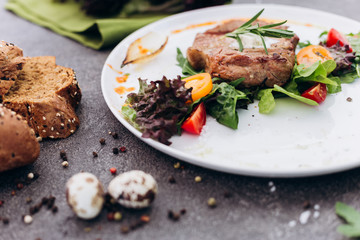 Grilled steak and vegetables on a dish with brown bread.