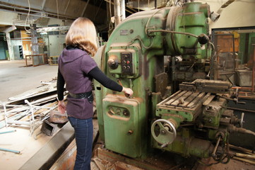 Fototapeta na wymiar girl turns the handle of the machine in an abandoned factory
