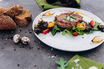 Grilled steak and vegetables on a dish with brown bread.