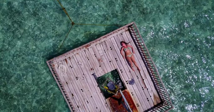 Young Woman Lies On A Wooden Raft In A Blue Lagoon And Sunbathes