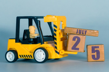 july 25th. Day 25 of month, Construction or warehouse calendar. Yellow toy forklift load wood cubes with date. Work planning and time management. summer month, day of the year concept