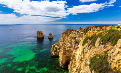 Fototapeta premium Panoramic view, Ponta da Piedade near Lagos in Algarve, Portugal. Cliff rocks and tourist boat on sea at Ponta da Piedade, Algarve region, Portugal. Ponta da Piedade, Algarve region, Portugal.