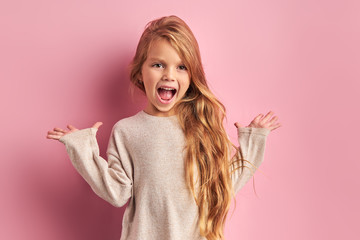 Portrait of screaming little girl with long hair, opened mouth. Isolated on pik background